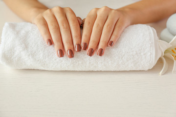 Obraz na płótnie Canvas Female hands with brown manicure on towel, closeup