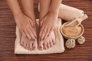 Female hands and feet with brown pedicure on towel