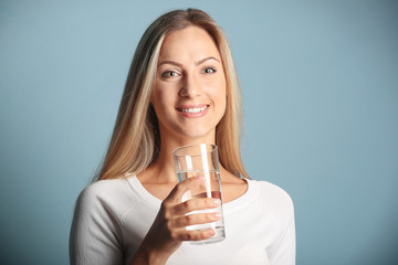 Beautiful girl drinking water on blue background
