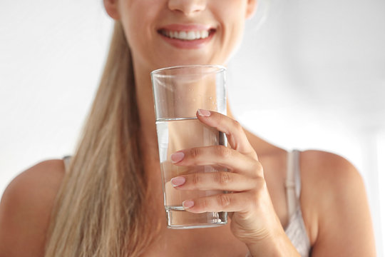 Girl drinking water on light background