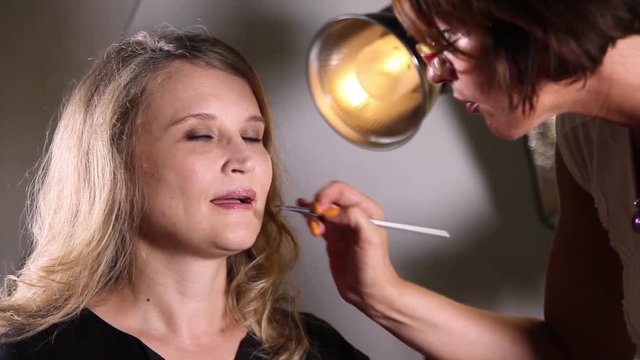 Professional makeup artist paints a female model's lips
