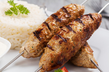 Barbecued kofta - kebeb with rice and vegetables on a plate.