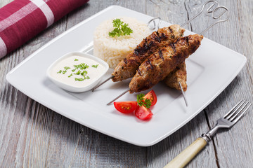 Barbecued kofta - kebeb with rice and vegetables on a plate.