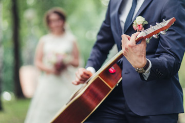 The groom plays the guitar for the bride during wedding ceremony