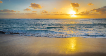 Fototapeta na wymiar Golden sunset as a rolls onto shore