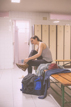Young brunette woman lace up boots in locker room