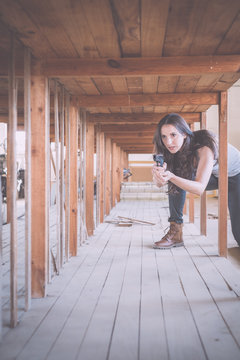Young brunette girl with gun standing on one knee