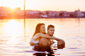 Fototapeta premium happy young couple having fun, man and woman in the sea on the beach. vintage retro style with soft focus and sun flare