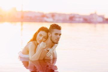 happy young couple having fun, man and woman in the sea on the beach. vintage retro style with soft focus and sun flare