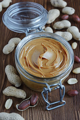 Peanut butter in a glass jar and peanuts