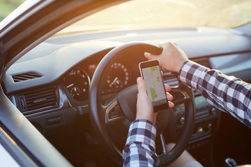 Man sitting in the car holding mobile phone with map gps navigation