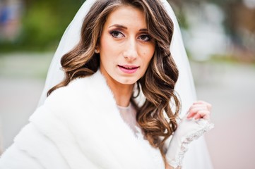 Portrait of charming curly bride in a fur coat