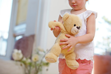 Kind trägt Kuscheltier mit beiden Händen