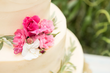Beautiful wedding cake with flowers, outdoors. Three levels