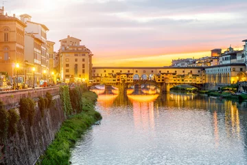 Fototapete Ponte Vecchio Illuminated cityscape view on Arno river with famous Ponte Vecchio bridge and buildings on the riverside on the sunset in Florence
