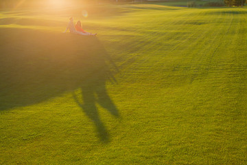 Obraz na płótnie Canvas Man and woman sitting on a hilltop together and hugging. Summer evening sunlight. A lot of sunny space. 