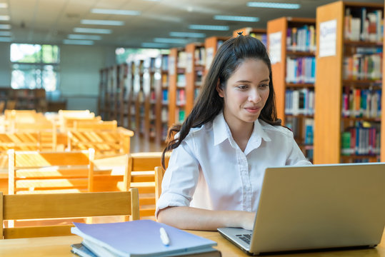 Indian / Asian college student working with laptop computer library.