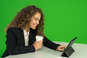 The businesswoman drink coffee and work with tablet on the green background