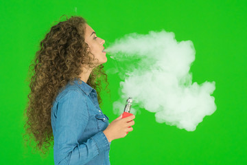 The young woman smoke electric cigarette on the green background