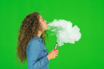 The cute woman smoke electric cigarette on the green background