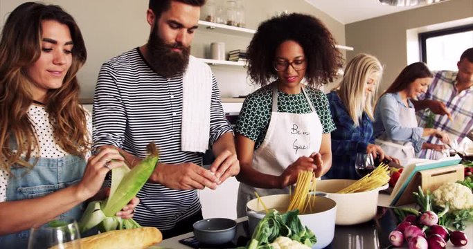 Group of multi racial friends cooking dinner in a kitchen