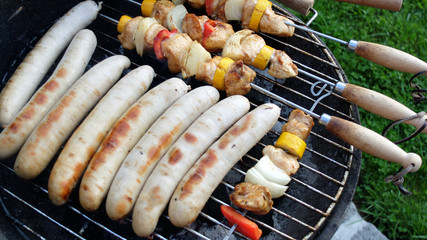 Fleischspiesse und Würstchen werden gegrillt