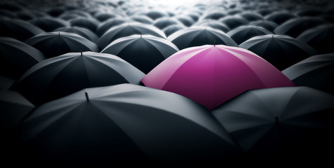Pink umbrella sticking out of the crowd, women power concept representation