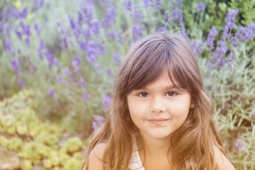 Portrait of attractive little girl outdoors in the sunlight. Blooming lavender are in the background.