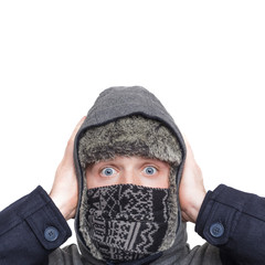 Young man in hat, scarf and hood hiding from the cold weather in the winter