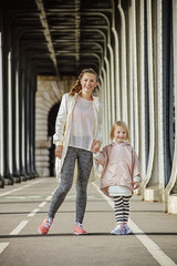 active mother and daughter standing on Pont de Bir-Hakeim bridge - obrazy, fototapety, plakaty