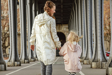 active mother and daughter on Pont de Bir-Hakeim bridge walking