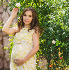 Pregnant woman in the garden is holding tummy