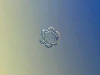 Snowflake sparkling on yellow-blue gradient background. This is macro photo of real snow crystal: tiny transparent plate with simple shape and inner structure, but beautiful relief surface.