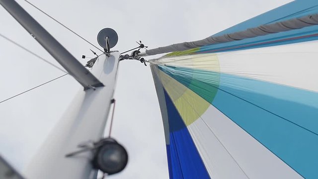 Multicolored Sailing in the wind through the waves. Full sails, very strong wind. Ocean race, real adventure. Real spray. Sun sails, and adventure. Sail blows in the wind on a boat. Slow motion shot.