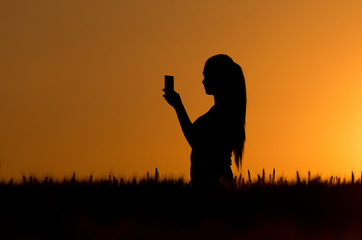 Silhouette of girl taking selfie