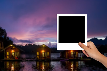 Blank photo frame on female hand and blurred travel photo