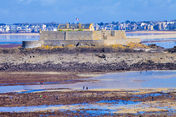 Obraz premium Pêche à pied sur la plage de Saint-Malo à marée basse, lors des grandes marées près du fort national