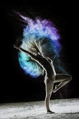 Fototapeta na wymiar Celebrate - Young dancer traces patterns through a cloud of powder as she dances against a dark background