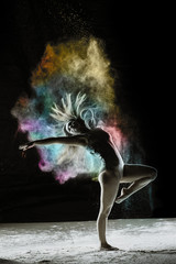 Fototapeta na wymiar Rebirth - Young dancer traces patterns through a cloud of powder as she dances against a dark background