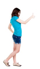 Back view of  woman thumbs up. Rear view people collection. backside view of person. Isolated over white background. slender brunette in a shorts shows the symbol of success or hitchhiking