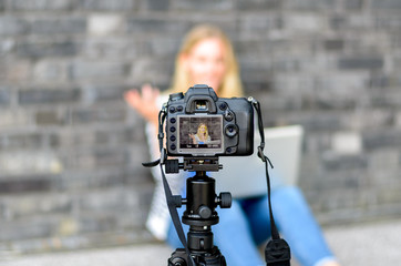 Young woman on camera LCD screen waving