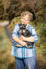 beautiful Senior smiling woman hugging her dog in the autumn outdoor