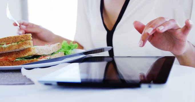 Woman eating lunch and using tablet computer