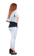 back view of standing beautiful red head woman. Young redhead girl in jeas. Rear view. Isolated over white background