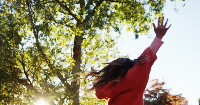 Girl outdoors turning and holding up hands