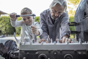Senior man and boy working on mechanism of a car
