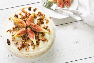 Decorative cake with fresh figs, crunchy walnut. White wooden table, top view.