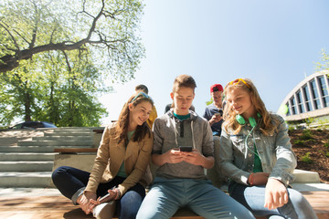 happy teenage friends with smartphones outdoors