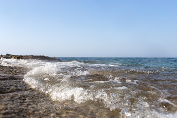 Fototapeta na wymiar Sea wave splashing over the shore rocks with a high sea spray