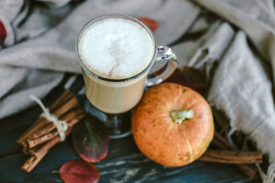 Spicy pumpkin latte on a wooden board with a sweater